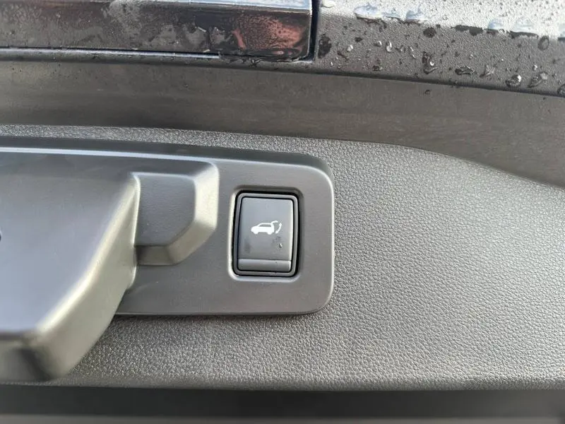 Bouton d'ouverture électrique du coffre sur panneau intérieur gris d'un Renault Scenic E-Tech Electric gris Schiste.
