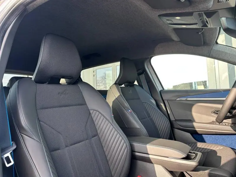 Vue intérieure côté avant droit du Renault Scenic E-Tech gris, sièges sport noirs avec surpiqûres bleues et logo Alpine.