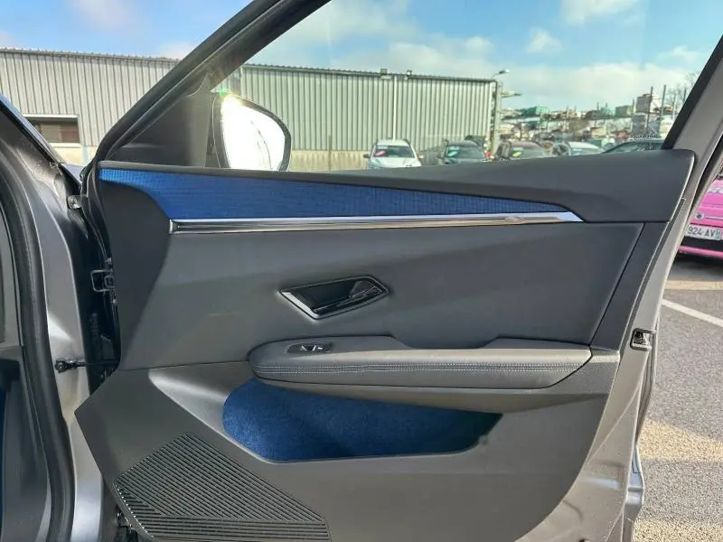 Vue côté gauche de la porte avant gris schiste du Renault Scenic E-Tech avec insert bleu et poignée noire brillante.