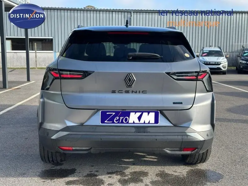 Vue arrière du Renault Scénic E-Tech gris schiste avec feux LED et logo central sur un parking extérieur.