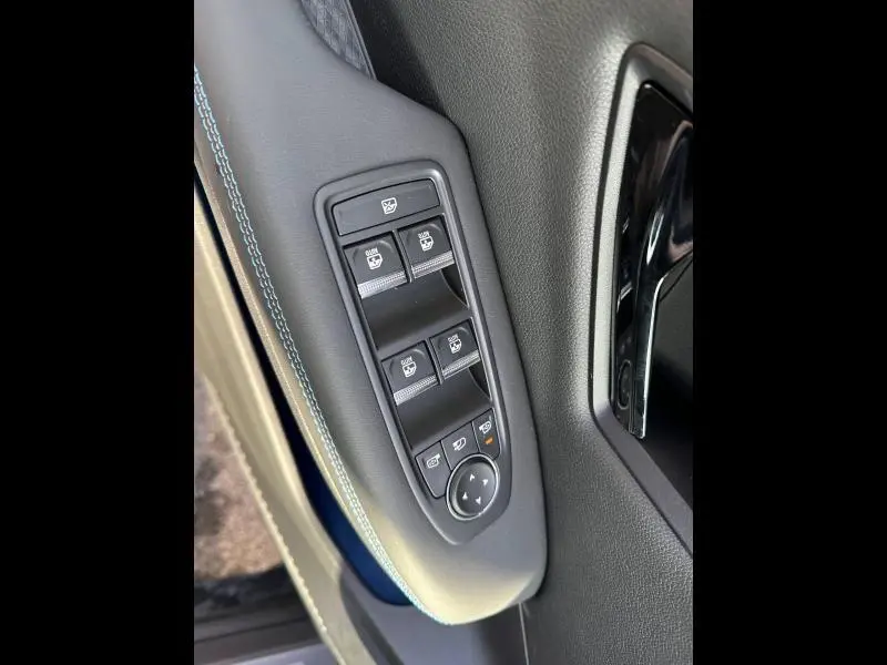 Gros plan sur les commandes des vitres électriques côté gauche du Renault Scénic E-Tech gris Schiste avec surpiqûres bleues.