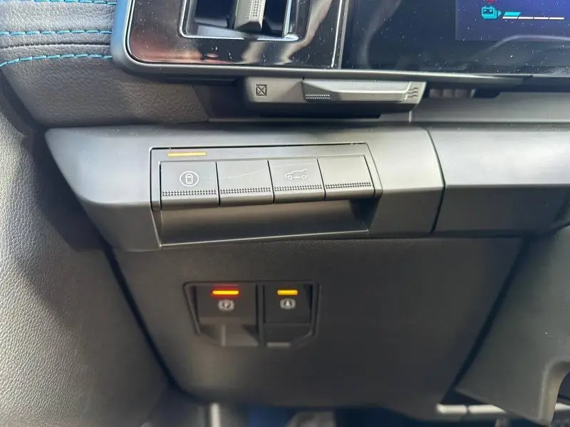 Gros plan sur les commandes de verrouillage et ouverture du coffre du tableau de bord gris du Renault Scenic E-Tech 2025.
