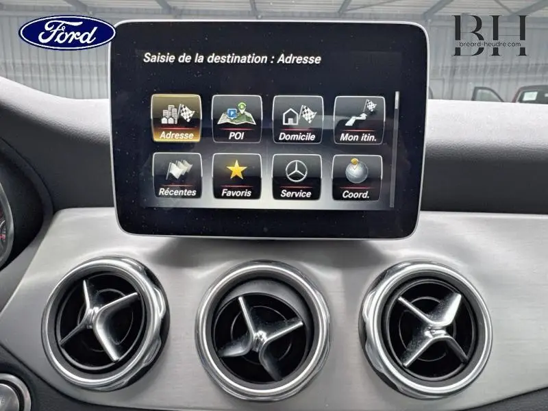 Vue intérieure centrée sur l'écran multifonction et les aérateurs circulaires chromés du Mercedes GLA 180 d noir cosmos.