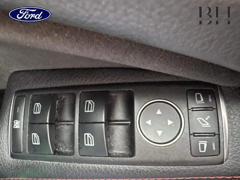 Vue rapprochée des commandes de lève-vitres et réglages des rétroviseurs sur porte côté gauche d'une Mercedes GLA noir cosmos de 2018.