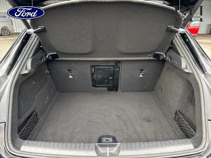 Coffre ouvert vu de l'arrière d'une Mercedes GLA 180 d Fascination noir cosmos, espace de chargement vide et propre.