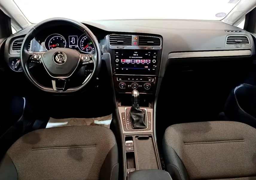 Vue intérieure avant de la Volkswagen Golf noire 2019, volant cuir multifonctions et console centrale avec écran tactile.