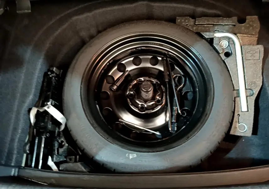 Vue plongeante sur la roue de secours et outils de bord dans le coffre d'une Volkswagen Golf noire 2019.