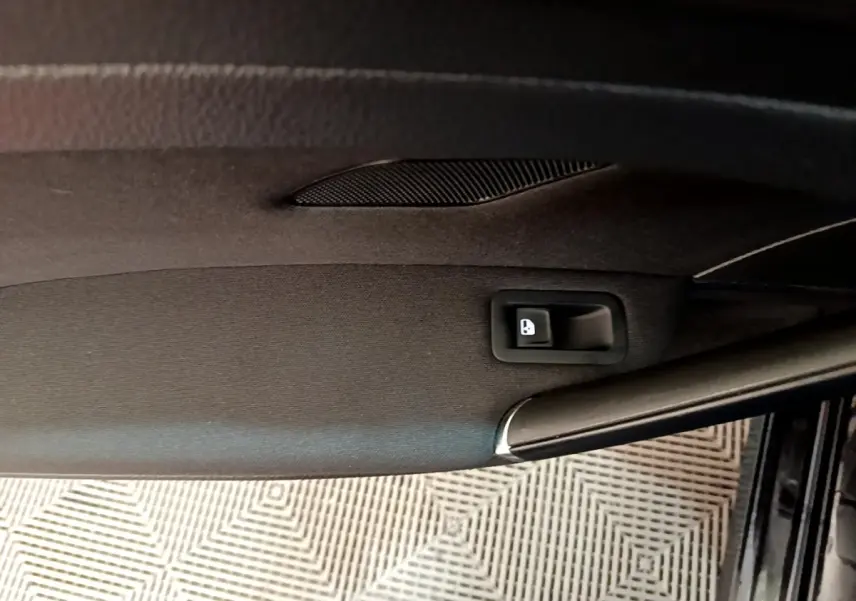 Vue rapprochée de la porte intérieure côté conducteur d’une Volkswagen Golf noire, bouton de verrouillage visible.
