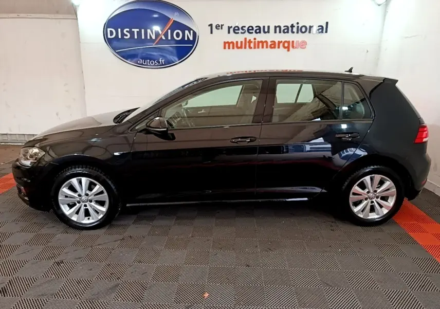 Profil côté gauche d'une Volkswagen Golf noire 2019 garée en intérieur avec jantes alliage et rétroviseurs électriques.