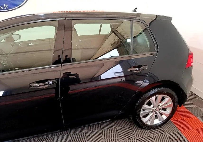 Vue latérale côté droit d'une Volkswagen Golf noire de 2019, mettant en valeur les jantes alliage et la carrosserie brillante.