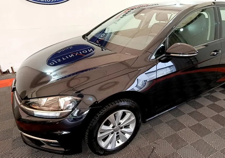 Vue 3/4 avant droite d'une Volkswagen Golf noire brillante avec jantes alliage et rétroviseur électrique.