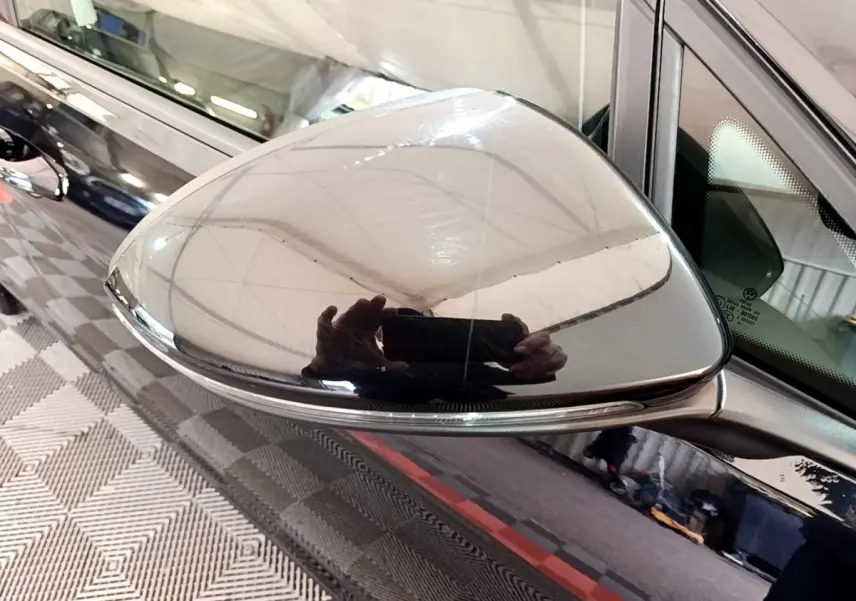 Rétroviseur droit noir brillant de Volkswagen Golf 2019, reflet net et carrosserie noire visible en arrière-plan.