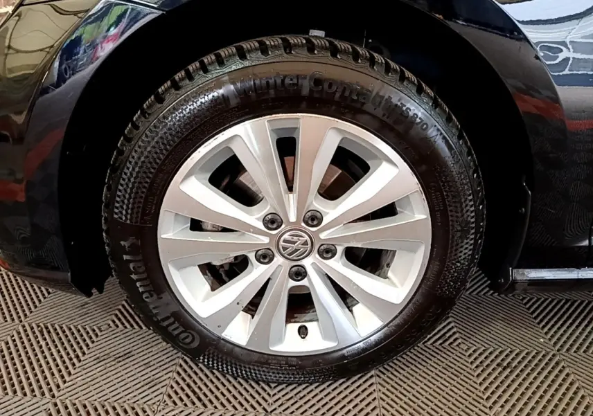 Gros plan sur la roue avant gauche d'une Volkswagen Golf noire, avec jante alliage et pneu hiver Continental.