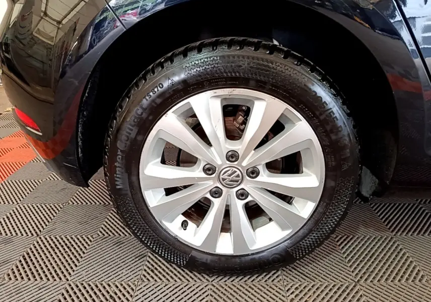 Gros plan sur la roue avant droite d'une Volkswagen Golf noire, avec jante alliage argentée et pneu hiver.