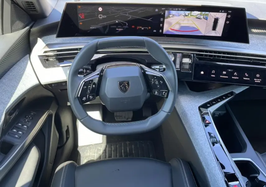Vue intérieure du poste de conduite du Peugeot 5008 Hybrid 145 allure e-dcs6 2025, volant cuir et grand écran tactile panoramique.