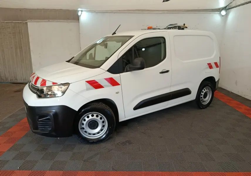 Vue 3/4 avant droite d'un Citroën Berlingo blanc 2021 avec bandes rouges réfléchissantes et toit équipé d'une rampe lumineuse.