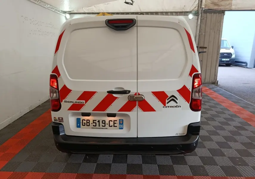 Vue arrière d’un Citroën Berlingo blanc 2021 avec bandes rouges diagonales de sécurité et plaque d’immatriculation française.