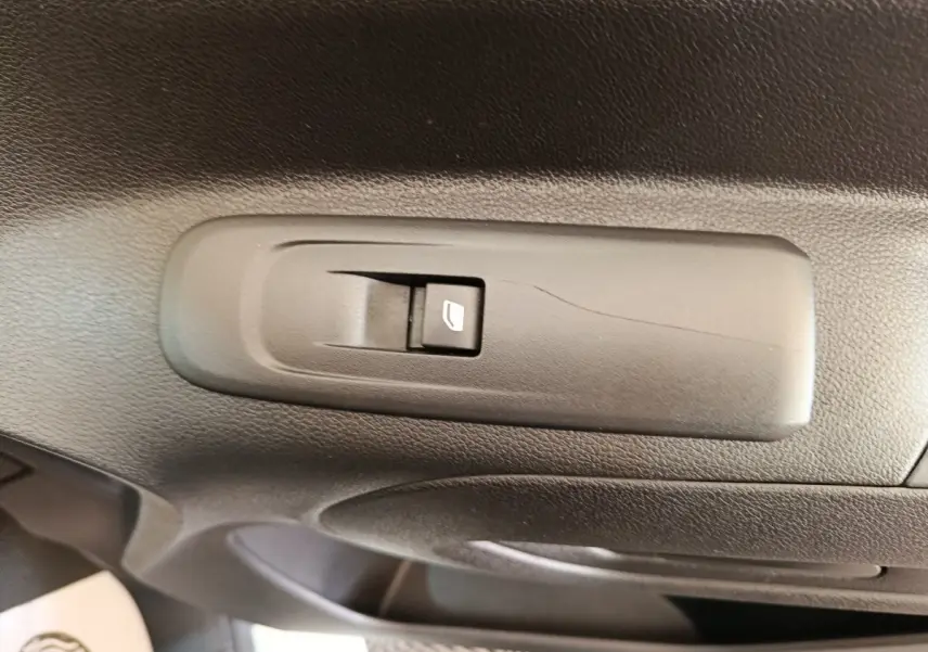 Gros plan sur l'interrupteur de lève-vitre côté conducteur dans l'intérieur noir du Citroën Berlingo blanc 2021.