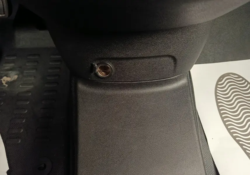 Détail de la prise 12V sur la console centrale noire du Citroën Berlingo blanc 2021, vue intérieure côté conducteur.