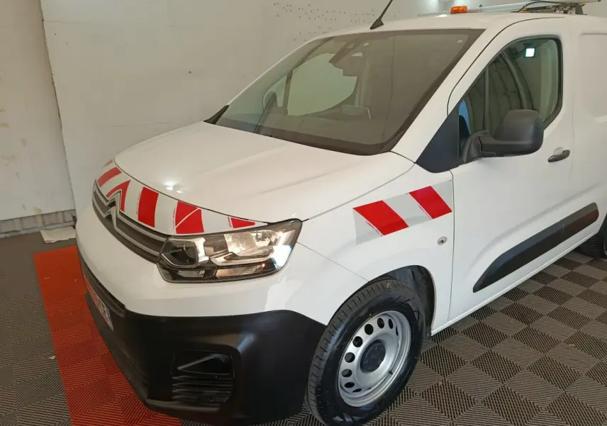Vue 3/4 avant droit d'un Citroën Berlingo blanc 2021 avec bandes rouges et blanches réfléchissantes sur le capot et l'aile.