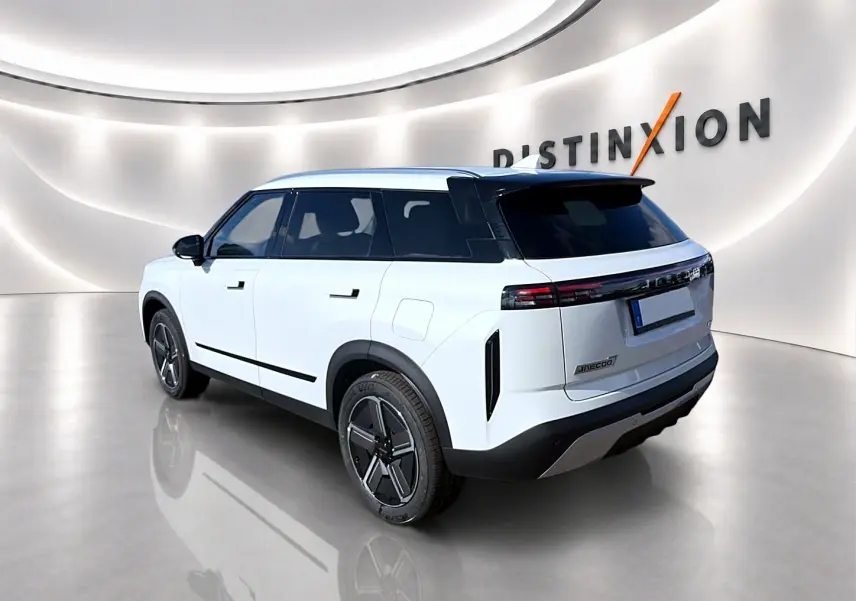 Vue 3/4 arrière droit du SUV JAECOO J7 blanc kaki avec toit noir et feux arrière LED continus dans un showroom moderne.