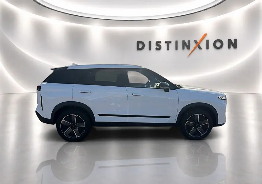 Vue de profil côté gauche du SUV JAECOO J7 blanc kaki avec toit noir et jantes alu noires dans un showroom lumineux.