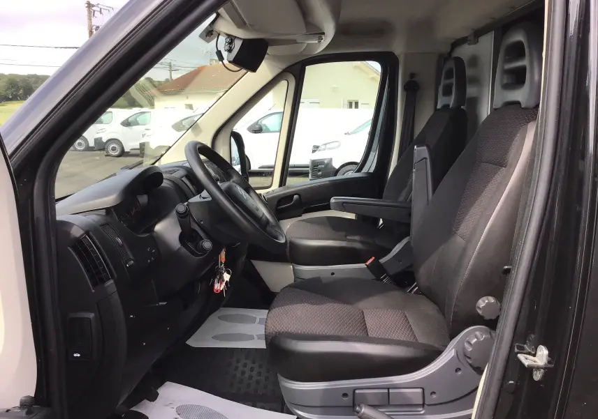 Vue intérieure côté conducteur du Citroën Jumper gris graphite, montrant les sièges avant et le tableau de bord.