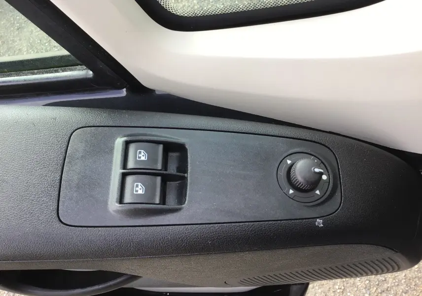 Gros plan sur la commande des vitres électriques et réglage des rétroviseurs côté conducteur du Citroën Jumper gris Graphito.