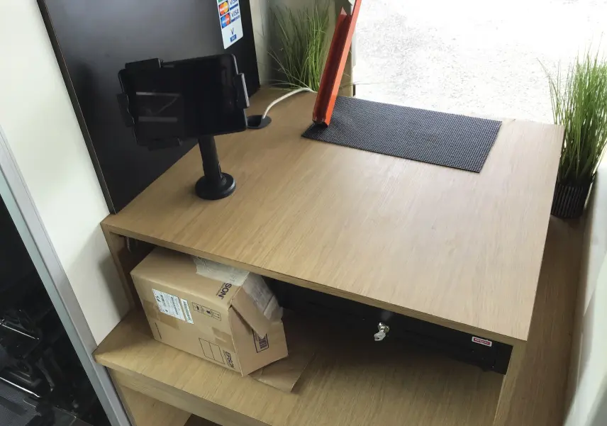 Plan de travail en bois clair avec caisse enregistreuse et support tablette dans un Citroën Jumper Food Truck gris.