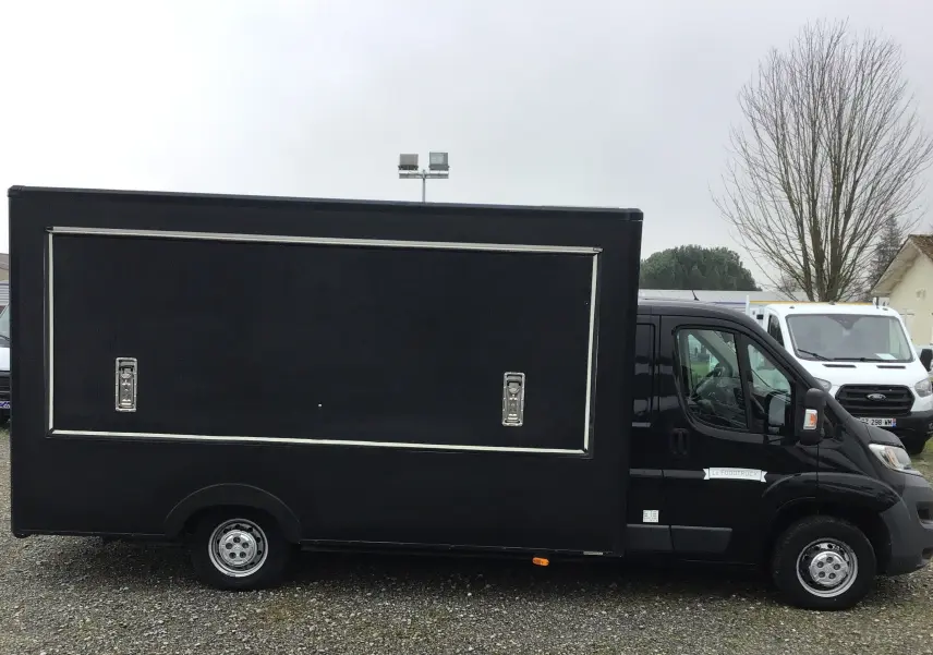 Vue de profil côté gauche d'un Citroën Jumper Food Truck gris graphito avec caisse magasin fermée.