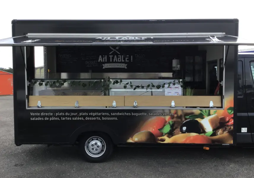 Vue latérale droite d'un Citroën Jumper gris Graphito aménagé en food truck avec vitrine et menu visible.