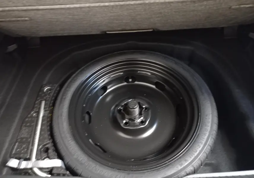 Roue de secours noire montée sur jante acier dans le coffre d'une Volkswagen Golf Bleu Anemone 2025.