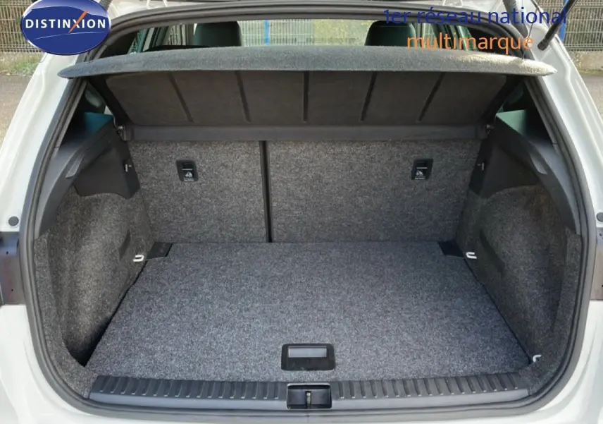 Coffre ouvert vu de l'arrière d'un SEAT Arona blanc avec toit noir, montrant un espace de chargement propre et vide.