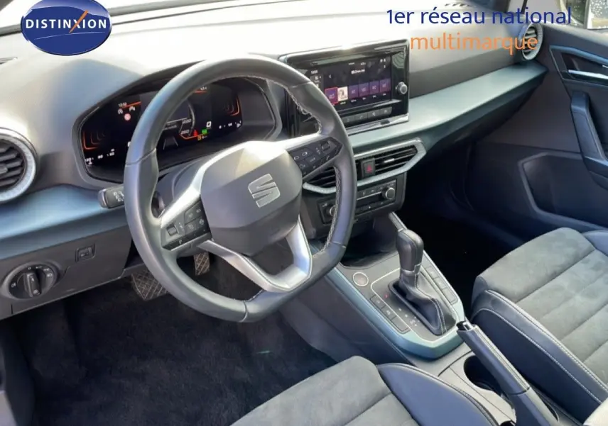 Vue intérieure du poste de conduite du SEAT Arona 2025, volant cuir multifonction et console centrale avec boîte automatique.