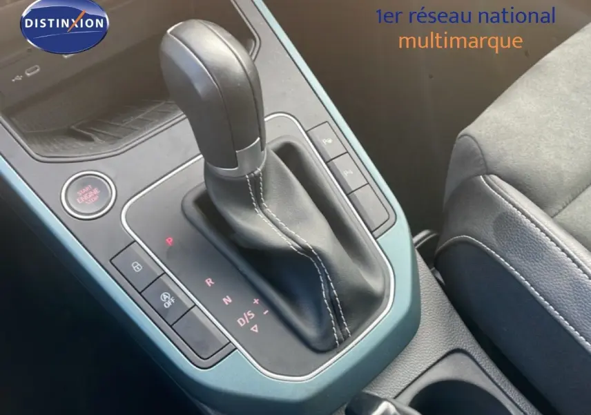 Gros plan sur la console centrale du SEAT Arona 2025, levier de vitesse automatique en cuir noir avec surpiqûres blanches.