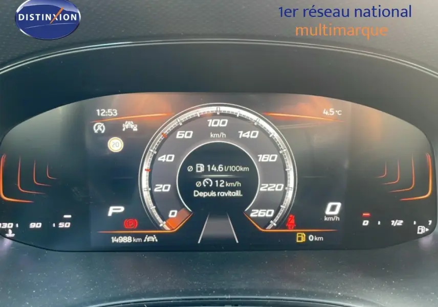 Vue rapprochée du tableau de bord numérique du SEAT Arona 2025, affichage de vitesse et consommation, ambiance orange.