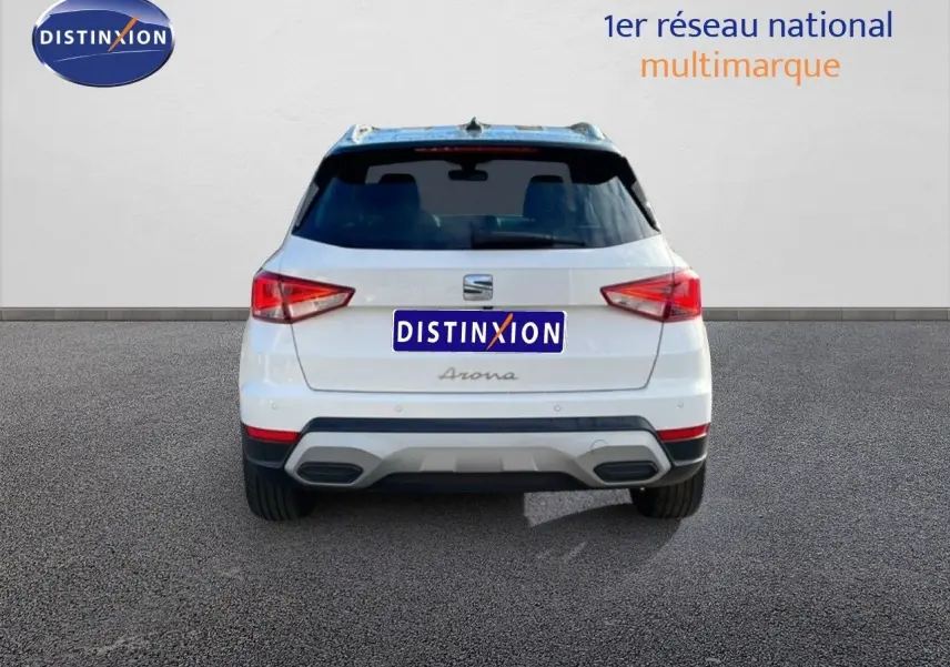 Vue arrière d’un SEAT Arona blanc avec toit noir, montrant ses feux arrière et double sortie d’échappement.