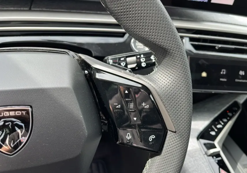 Gros plan sur le volant cuir perforé gris avec commandes multifonctions du Peugeot 5008 Hybrid 145 GT Alcantara.