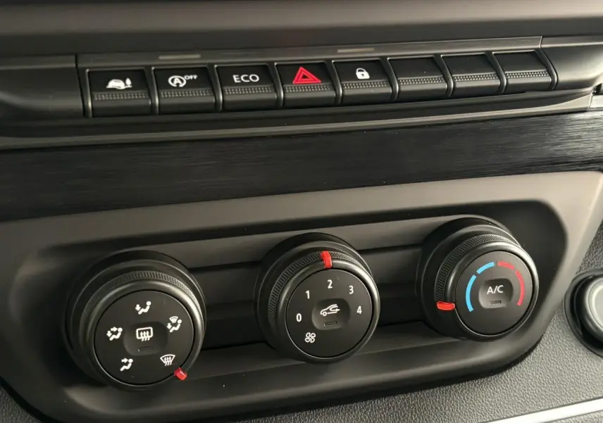 Détail des commandes de climatisation et boutons de fonction sur le tableau de bord du Renault Trafic Fourgon blanc.