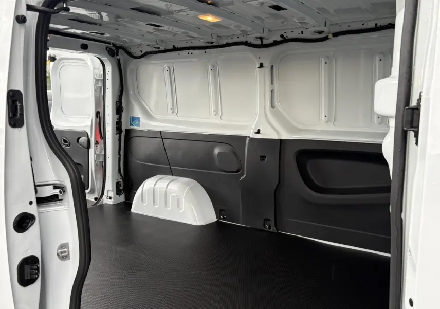 Intérieur du Renault Trafic Fourgon blanc Glacier vu de l’arrière, montrant le plancher bois et la cloison tôlée.