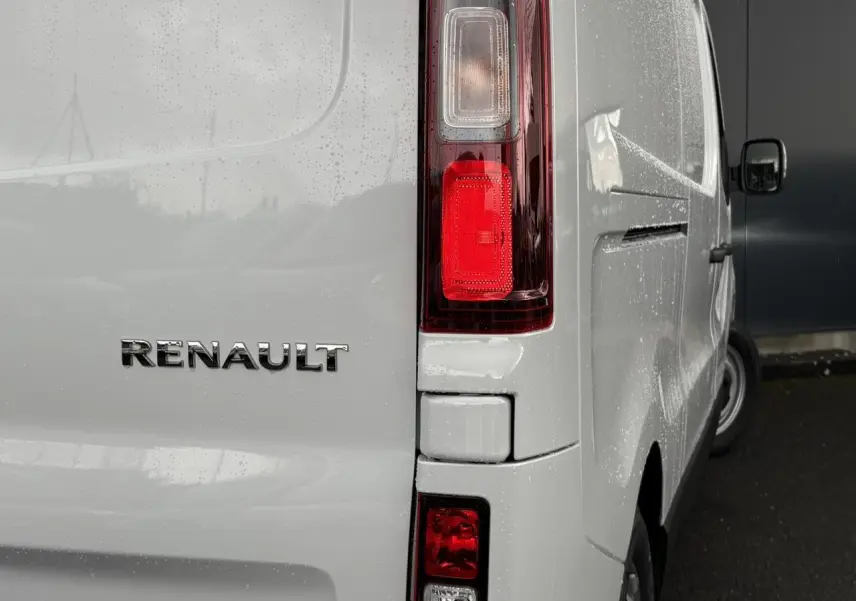 Vue arrière droite du Renault Trafic Fourgon blanc Glacier avec feux arrière verticaux et logo Renault visible.