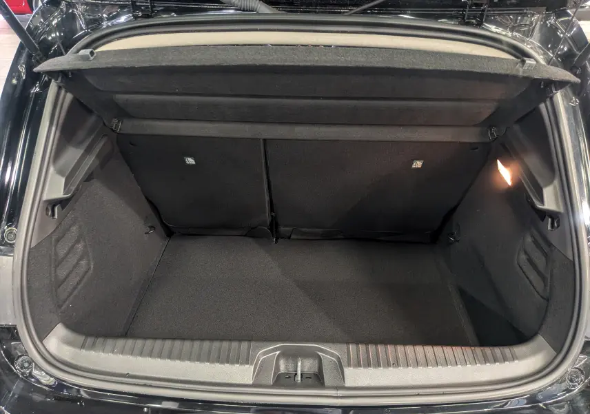 Coffre ouvert vu de l'arrière d'une Renault Clio V noire, montrant un espace de chargement propre et éclairé.