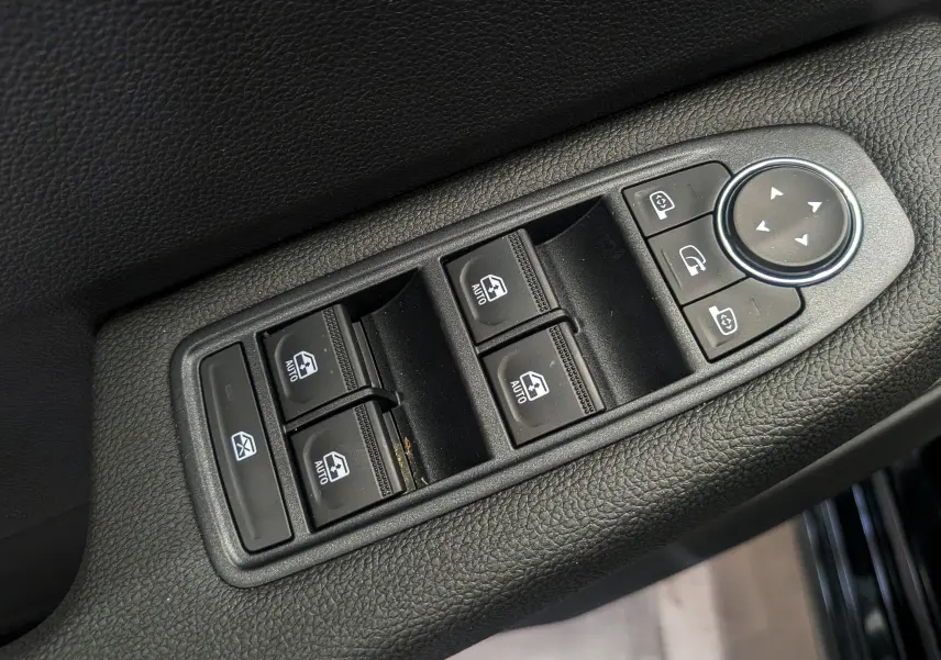 Gros plan sur les commandes de lève-vitres et rétroviseurs côté gauche d’une Renault Clio V noire 2025.