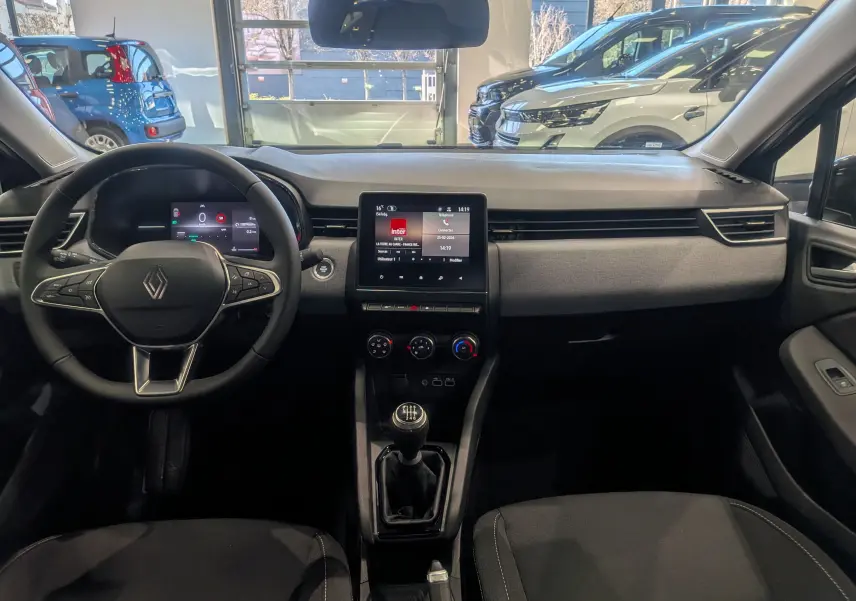 Vue intérieure avant de la Renault Clio V noire, mettant en valeur le tableau de bord moderne avec écran tactile et boîte manuelle.