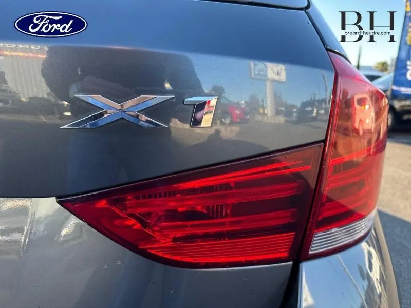 Gros plan sur le feu arrière droit et le logo X1 d'une BMW X1 Mineralgrau vue de l'arrière.