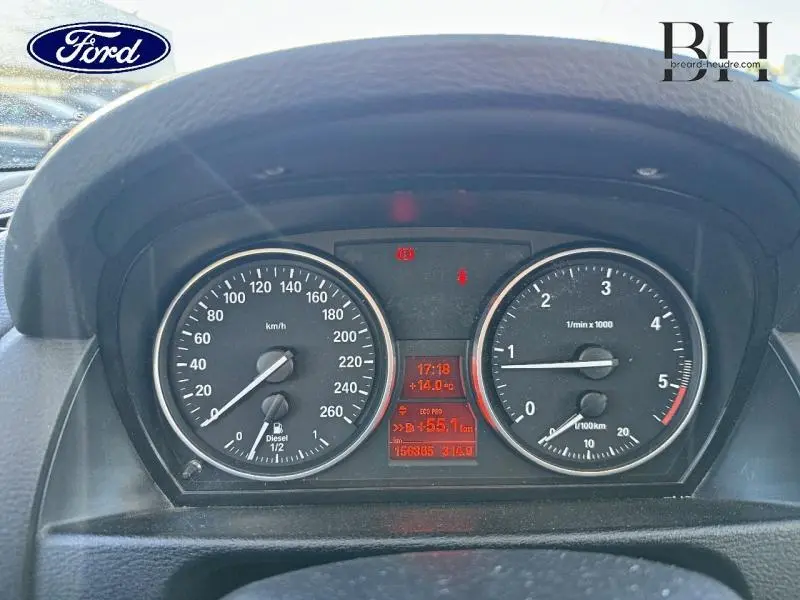 Vue rapprochée du tableau de bord d'une BMW X1 Mineralgrau de 2013, affichant compteur et compte-tours noirs.