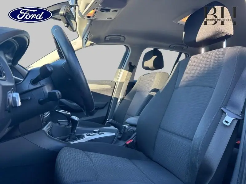 Vue intérieure côté conducteur de la BMW X1 Mineralgrau 2013, montrant les sièges avant et le volant cuir sport.