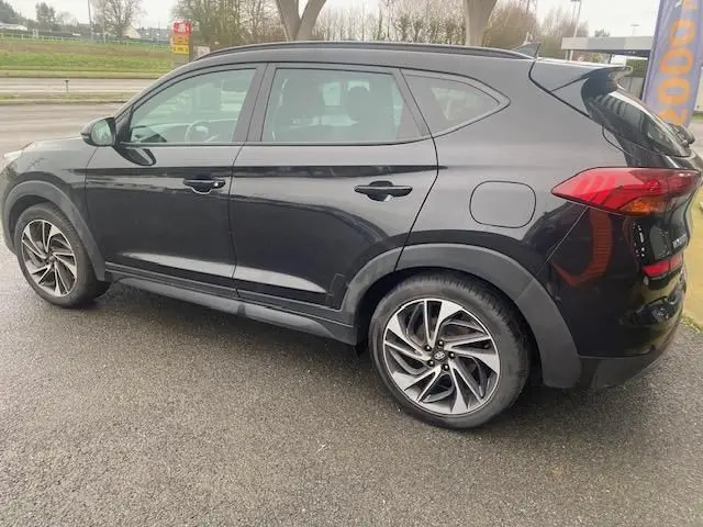 Vue de profil côté gauche d’un Hyundai Tucson noir 2019 avec jantes alliage bi-ton et feux arrière visibles.