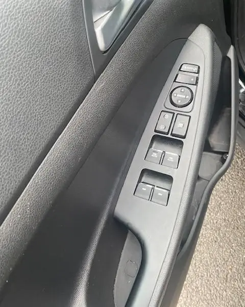 Vue rapprochée de la commande des vitres et rétroviseurs côté gauche intérieur d’un Hyundai Tucson noir de 2019.
