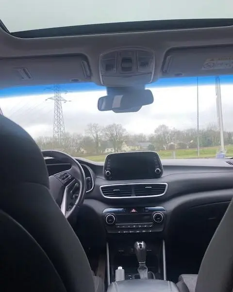 Vue intérieure avant du Hyundai Tucson noir 2019, montrant tableau de bord, écran tactile et volant côté gauche.